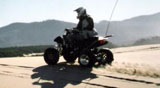 Bob riding our black 400cc LTZ Suzuki quad against a sunny dune crest on a winter morning