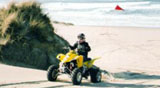 Judy riding our Suzuki 400 near the ocean at Sand Lake